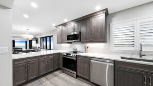 A modern kitchen with dark wood cabinets, stainless steel appliances, and a large island. - Updated direct oceanfront corner 2/2 with a large balcony and heated beachfront pool (New Smyrna Beach)