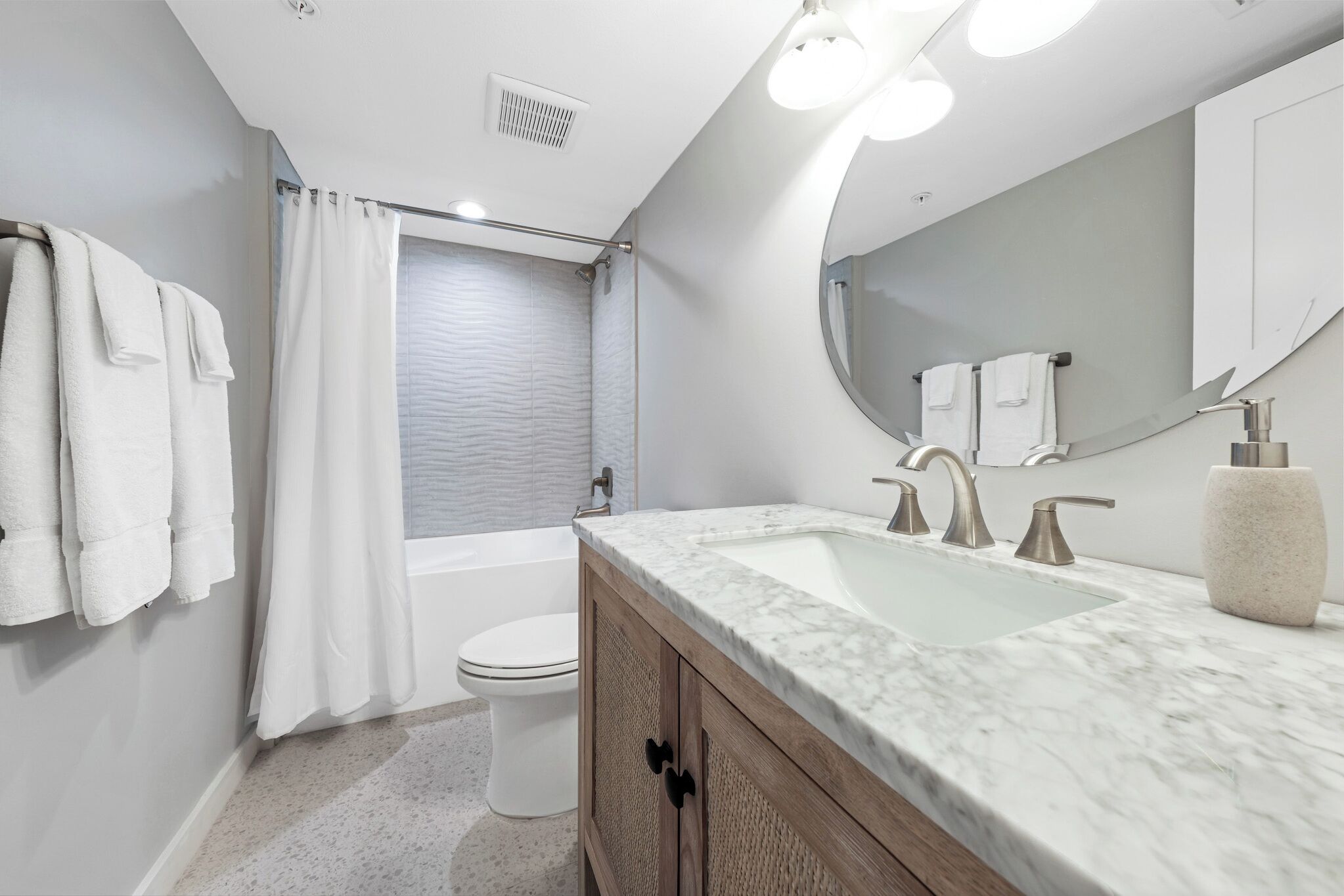 A modern bathroom with a marble sink, a large mirror, and a shower area.