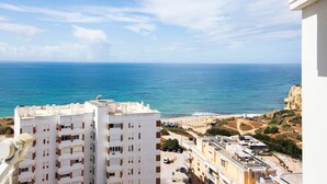 Un immeuble de grande hauteur doté de nombreux balcons, offrant une vue sur une zone côtière avec une plage et des falaises.