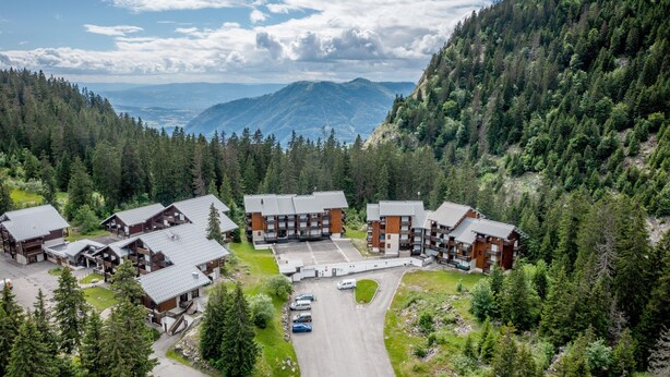 A lodge with multiple buildings, a parking area, and a mountainous backdrop. - Apartment 'Fleury' with Mountain View and Balcony (Mieussy)