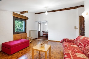 Una stanza con un divano rosso, un tavolo in legno e un divano rosso decorato.