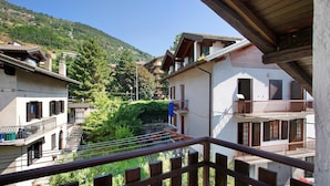 Ein Wohngebäude mit Balkon, Treppe und Blick auf einen Hügel.