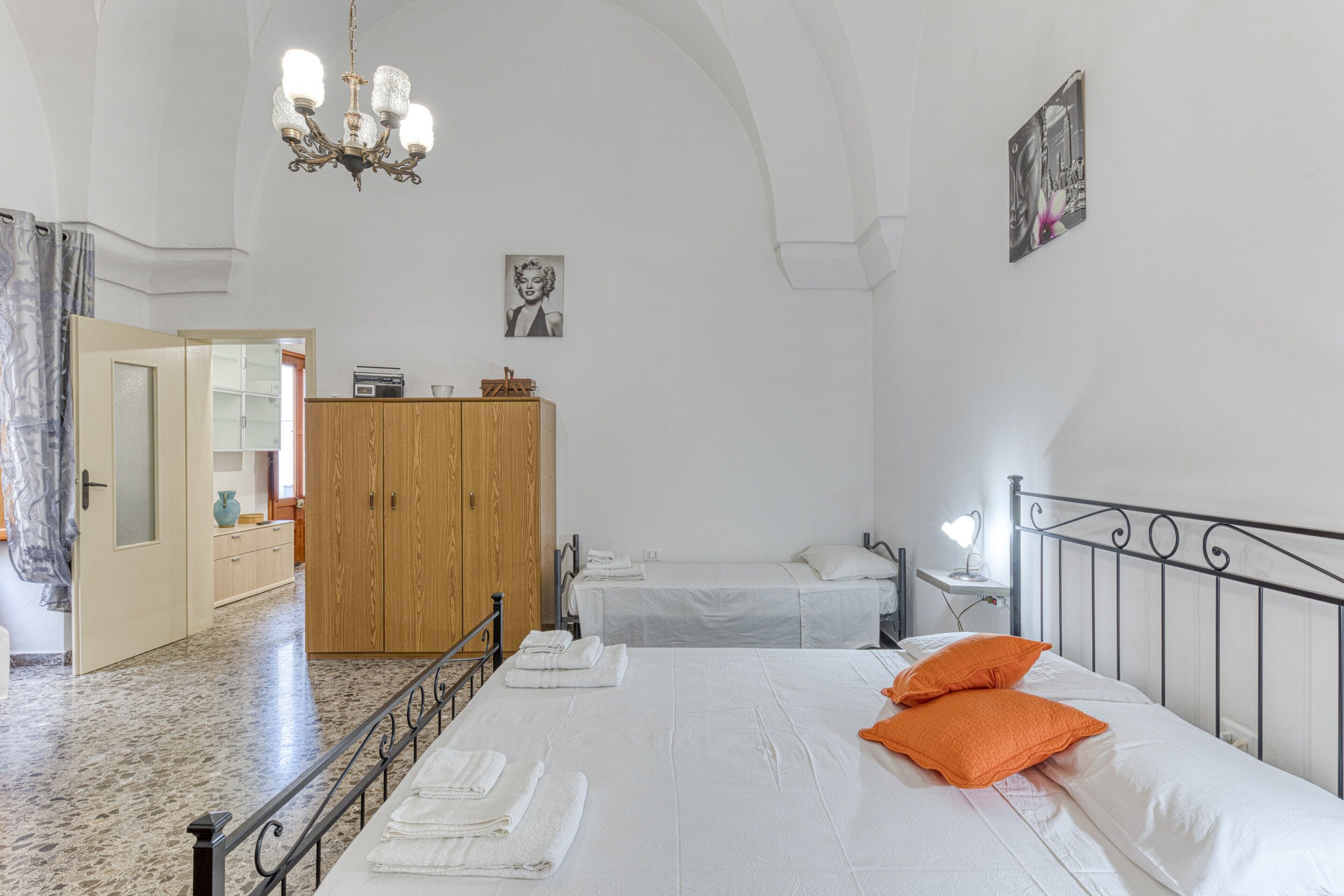 A bedroom with a bed, a wardrobe, a mirror, and a chandelier.