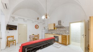 Een slaapkamer met een bed, een klein kitchenette, een badkamer en een eethoek.