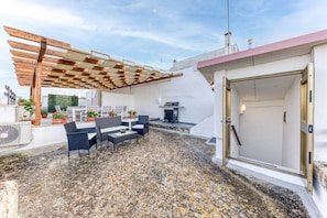 An outdoor patio with a pergola, seating area, and a grill. - Studio Apartment 'Noemi' with Shared Terrace and Air Conditioning (Presicce-Acquarica)