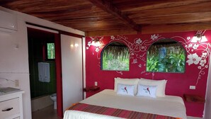 Ein Schlafzimmer mit Bett, Kommode und einem Fenster mit Blick auf Grün.