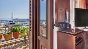 A balcony with potted plants, a wooden cabinet, and a television.