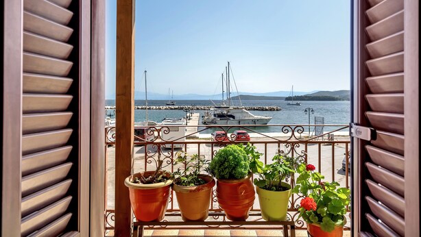 A balcony with potted plants and a view of a marina with boats.