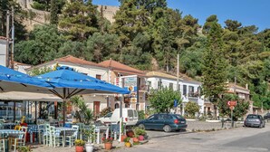 A street with outdoor seating, a white van, and a blue umbrella.