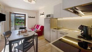 Een moderne keuken met een eethoek, een koffieapparaat en uitzicht op een tuin.