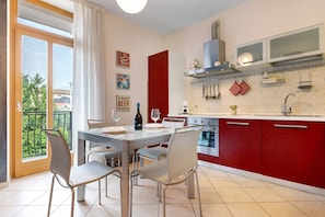 A modern kitchen with red cabinets, a dining area with a table and chairs, and a large window with a view of greenery.