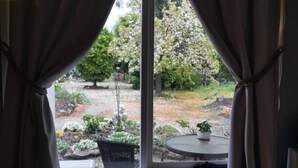 A room with a window, curtains, a chair, and a small table. - Harvest Home (Avenel)