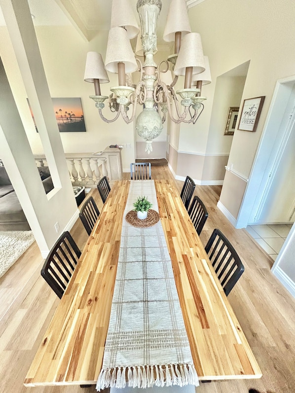A dining room with a wooden table, black chairs, a central rug, and a chandelier.