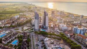 Vista aérea de una ciudad costera con modernos edificios altos, un puerto deportivo y una playa.