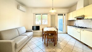 Una cocina compacta con una mesa de comedor, un sofá y un televisor.