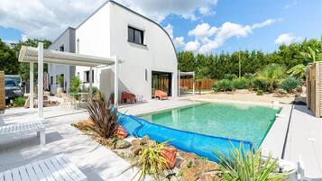 Une maison moderne dotée d’une piscine, d’une façade blanche et d’un patio couvert.