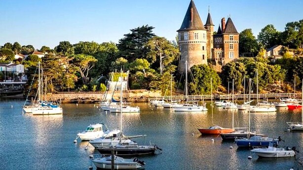 A historic building with a tower, surrounded by a marina with various boats. - Modern Villa with Private Pool (Saint-Aignan-Grandlieu)