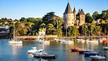 Un bâtiment historique doté d’une tour, entouré d’un port de plaisance où sont amarrés différents types de bateaux.