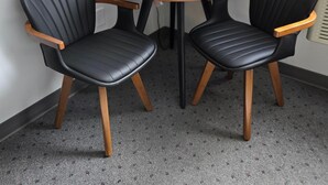 A small round table with two black leather chairs, a black floor lamp, and a coffee maker on the table. - Piper's Inn (Clearbrook)