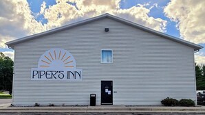 A white building with a sign reading "Piper's Inn" and a sun graphic. - Piper's Inn (Clearbrook)