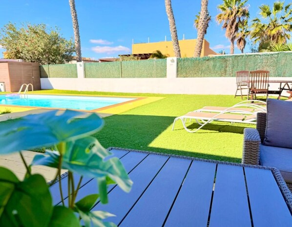 A backyard with a pool, artificial grass, and outdoor furniture. - Villa Solara | Sleeps 7| Private Pool & Aircon (Castillo Caleta de Fuste)