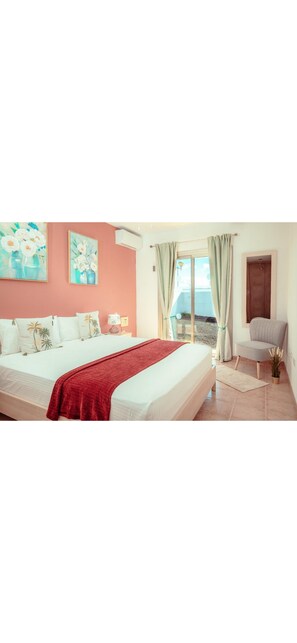 A bedroom with a bed, a chair, a window with curtains, and a painting on the wall. - Villa Solara | Sleeps 7| Private Pool & Aircon (Castillo Caleta de Fuste)