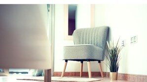 A modern chair with wooden legs, a small potted plant, and a light-colored floor.