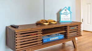A wooden entertainment center with a board game, a remote control, and a WiFi sign. - Modern, renovated, centrally located condo with self check in and parking (Ocean City)