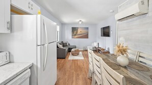 A modern kitchen with white cabinetry, a built-in oven, and a dining area with a wooden table and chairs. - Modern, renovated, centrally located condo with self check in and parking (Ocean City)
