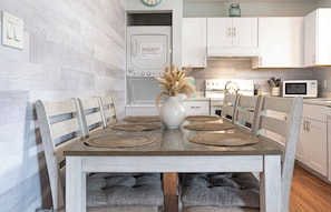 A dining table with four chairs, a vase with dried plants, and a microwave in the background. - Modern, renovated, centrally located condo with self check in and parking (Ocean City)