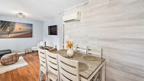 A dining area with a wooden table, chairs, and a painting on the wall. - Modern, renovated, centrally located condo with self check in and parking (Ocean City)