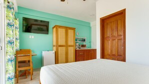Une chambre à coucher avec un lit, une armoire en bois, un bureau avec une chaise et un téléviseur fixé au mur.