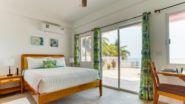 Une chambre avec un lit, une chaise, une table et une vue sur la plage.