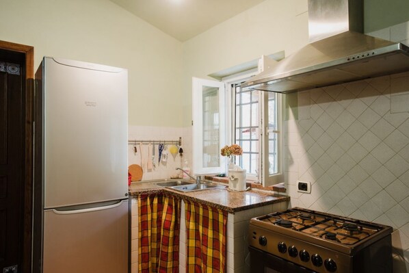 Een koelkast, een kookplaat, kookgerei, borden en bestek