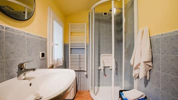 Un bagno con un lavandino grande, uno spazio doccia e un portasciugamani.