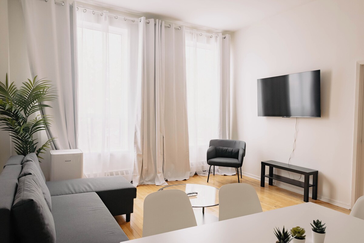 A modern living room with a sofa, a coffee table, a TV mounted on the wall, and a bench.