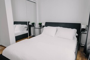 Een moderne hotelkamer met een groot bed, nachtkastjes, een spiegel en een kleine plant.