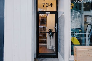 Fachada con un cartel con el número '734' sobre la entrada, un letrero que dice 'Mantener Cerrado, Por Favor' y un letrero de 'Sale Rick' visible a través del ventanal.