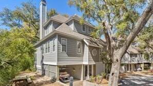 Una casa a due piani con garage, immersa tra alberi e un prato curato.