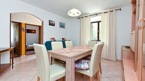 A dining area with a wooden table, four chairs, and a hanging light fixture. - Apartment 2331/111619 (Istria - Fažana), 150m from the beach (Fažana)