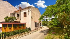 A narrow street with buildings on both sides, a clear sky, and lush greenery. - Apartment 2331/111619 (Istria - Fažana), 150m from the beach (Fažana)