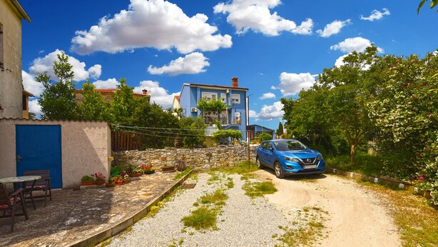 A rural road with a blue car parked on the side, surrounded by greenery and a stone wall. - Apartment 2331/111619 (Istria - Fažana), 150m from the beach (Fažana)