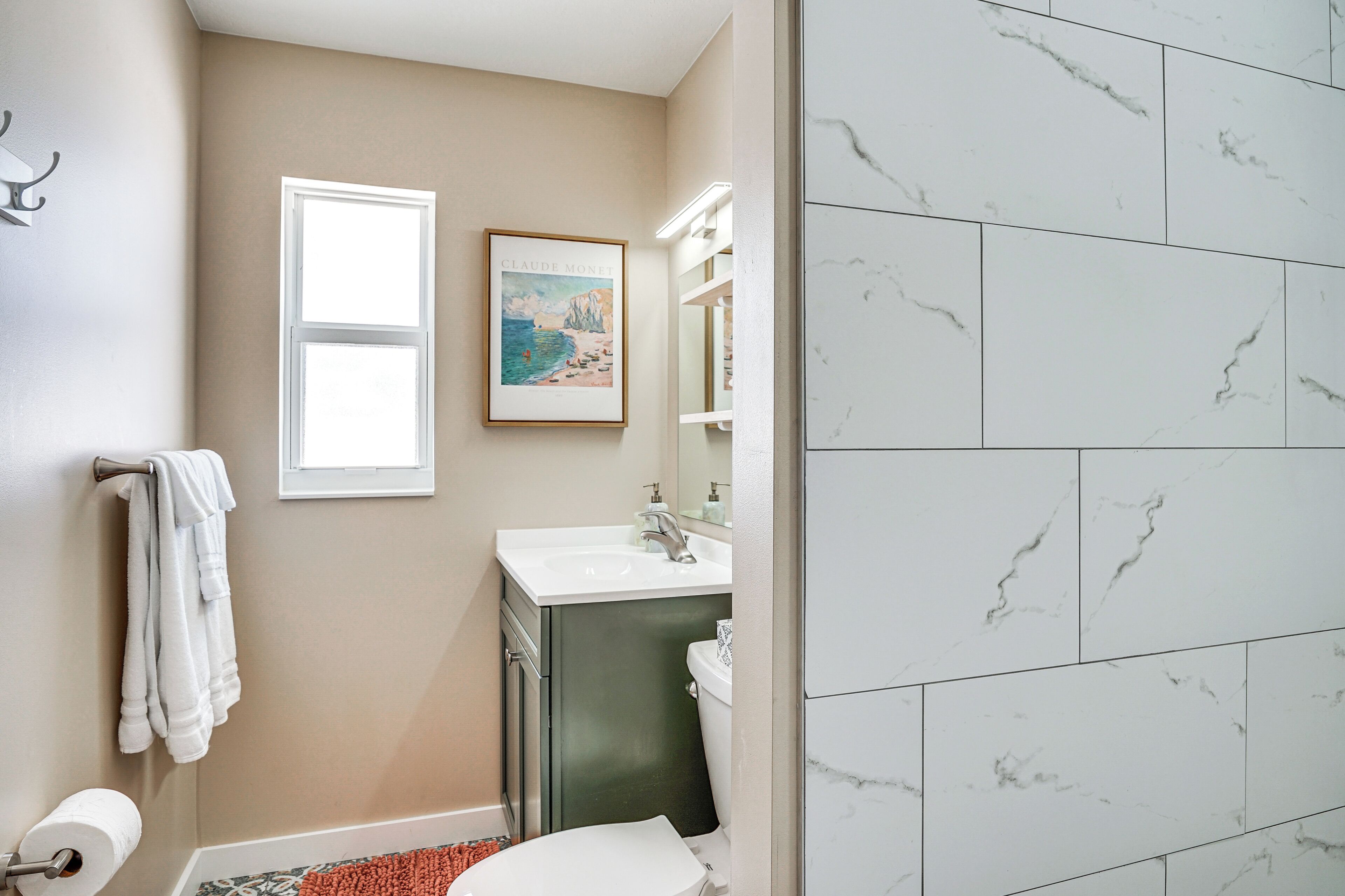 A bathroom with a toilet, sink, and towel rack.
