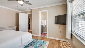 A bedroom with a bed, a ceiling fan, a TV mounted on the wall, and a window with blinds. - 1 Block to Shore: Fort Myers Beach Retreat (Fort Myers Beach)