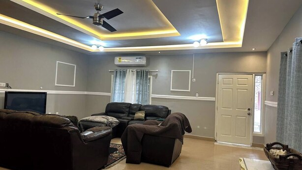 Un salón con un conjunto de sofás, ventilador de techo, iluminación empotrada y aire acondicionado.