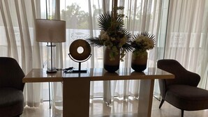 Une pièce moderne avec une table à plateau en verre, deux chaises, une lampe et des vases décoratifs ornés de fleurs.