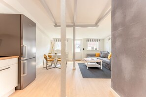 A modern kitchen with a built-in refrigerator and a dining area with yellow chairs.