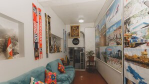 A hallway with a teal sofa, colorful pillows, and a potted plant. - Lucios Hostal (Cusco)