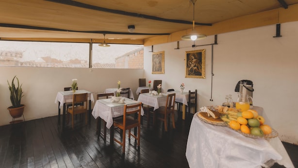 A dining area with tables set for breakfast, featuring a fruit display and a coffee station. - Lucios Hostal (Cusco)