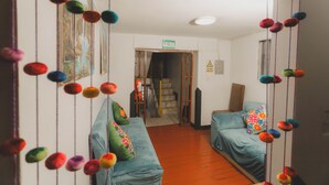 A hotel room with two beds, colorful pillows, a wooden floor, and a staircase leading to the exit. - Lucios Hostal (Cusco)
